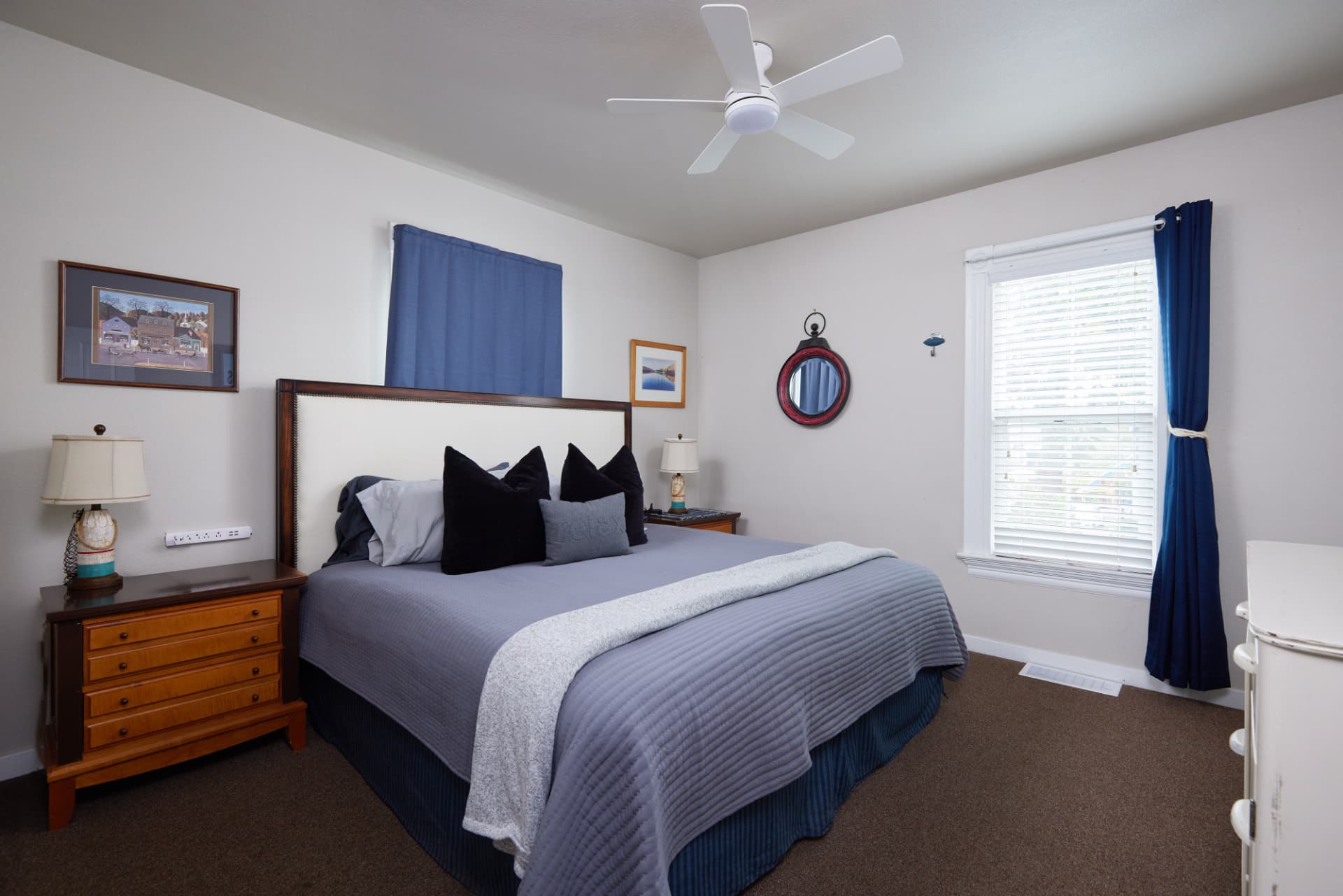 The Harbor bedroom with navy accents and a ceiling fan